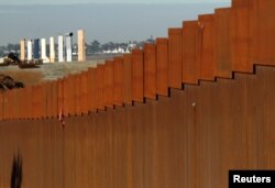 FILE - Prototypes for President Donald Trump's border wall are seen behind a border fence between Mexico and the United States, in Tijuana, Mexico, Jan. 7, 2019.