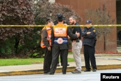 Police officers guarding the Tree of Life Synagogue following a shooting there speak with men in orange vests from a Jewish burial society in Pittsburgh, Pa., Oct. 27, 2018.