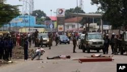 FILE - Bodies of people killed during anti-Kabila protests lie in the street as Congolese troops stand by, in Kinshasa, Democratic Republic of Congo, Sept. 19, 2016.