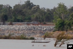 FILE - A fishing boat passes near a construction site of the Don Sahong dam, near the Cambodia-Laos borders, in Preah Romkel village, Stung Treng province, northeast of Phnom Penh, Cambodia, June 20, 2016.