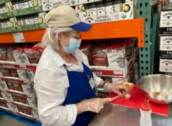 Seorang petugas menyiapkan sampel roti untuk dibagikan kepada calon pembeli di Costco, Lone Tree, Colorado, Kamis, 17 Juni 2021. (AP)