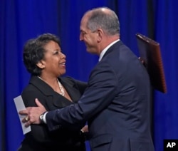 Attorney General Loretta Lynch, left, and Louisiana Gov. John Bel Edwards hug after Edwards delivered remarks during a memorial service for three law enforcement officers. (Bill Feig/The Advocate via AP)