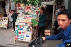 FILE - A young motorcyclist stops to buy a pack of cigarettes from a street-side vendor in Hanoi, May 12, 1999.