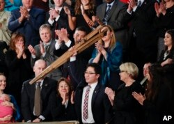 Ji Seong-ho holds up his crutches after being acknowledged by President Donald Trump during Trump's address to a joint session of Congress on Capitol Hill in Washington, Jan. 30, 2018.