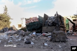 This image provided by the Syrian anti-government group Aleppo 24 news, shows damaged trucks carrying aid, in Aleppo, Syria, Sept. 20, 2016.