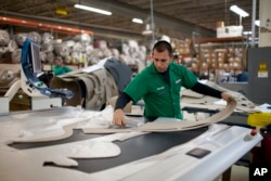 FILE - A worker manufactures car dash mats at a factory belonging to the TECMA group in Ciudad Juarez, Mexico, Dec. 27, 2013.