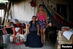 Ximena, 26, an indigenous Zapotec transgender woman, poses for a photo next her mother inside her house destroyed after an earthquake Sept. 10, 2017.