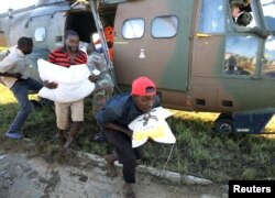 Workers offload food aid from a helicopter in the aftermath of Cyclone Idai, in Buzi, Mozambique, March 25, 2019.