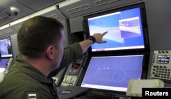 A U.S. Navy crewman aboard a P-8A Poseidon surveillance aircraft views a computer