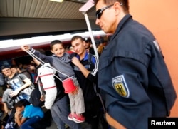 A child plays as migrants are taken out of trains by the police near the border with Austria in Freilassing, Germany, Sept. 15, 2015.
