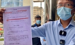 香港新同盟荃湾区议员谭凯邦展示一张香港市民接受中资公司中龙作免费病毒检测的”知情同意书”（美国之音/汤惠芸）