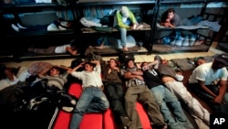 FILE - In this April 28, 2010, file photo, men look for a place to sleep in a crowded shelter for migrants deported from the United States, in the border city of Nogales, Mexico.