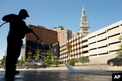 FILE - A worker cleans the sidewalk in front of Quicken Loans Arena in Cleveland, Aug. 5, 2015, before a Republican presidential candidates debate. The arena will also be the site of the party's national convention July 18-21.