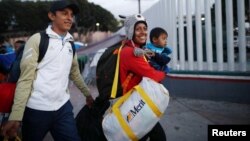 A family, members of a caravan of migrants from Central America, enter the United States border and customs facility, where they are expected to apply for asylum, in Tijuana, Mexico, May 2, 2018.