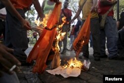 Supporters of Venezuela's President Nicolas Maduro burn a flag of the opposition party Popular Will (Voluntad Popular) close to the National Assembly in Caracas, Jan. 5, 2016.