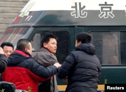 FILE - Zhang Xuezhong (C), a lawyer for Chinese dissident Zhao Changqing, argues with plain-clothed policemen as he refuses to show them his identification card when he was stopped and questioned by them on his way to court to attend Zhao's trial in Beijing January 23, 2014.