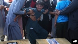A relative wails near the coffins of victims of the Dubai City wedding hall bombing during a mass funeral in Kabul, Afghanistan, Sunday, Aug.18, 2019.(AP Photo/Rafiq Maqbool)
