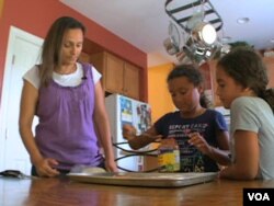 Wafaa Elmahgob cooks with her daughter, Nourene Nabbus, and her niece. (VOA)