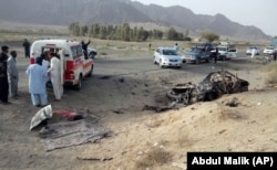 FILE - Volunteers stand near the wreckage of a destroyed vehicle, in which Mullah Akhtar Mansour was allegedly traveling in the Ahmed Wal area in Baluchistan province of Pakistan, near the Afghanistan border, May 21, 2016.