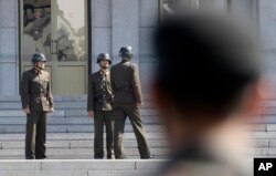FILE - Three North Korean soldiers talk to each other as a South Korean soldier watches, at the border village of Panmunjom in the Demilitarized Zone between North and South Korea, April 18, 2018.
