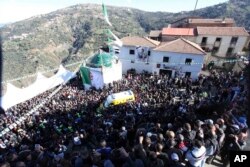The ambulance convoy carrying the coffin of Hocine Ait Ahmed, a national hero of the independence war with France, arrives for a burial ceremony in Ath Ahmedh, Algeria, amid a crush of thousands seeking to pay respects, Jan.1, 2016.