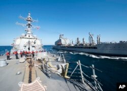 FILE - Guided-missile destroyer USS Bulkeley participates in a replenishment-at-sea with fleet replenishment oiler USNS John Lenthall in the Gulf of Oman. Iranian naval vessels conducted rocket tests last week near the USS Harry S. Truman aircraft carrier.