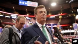 FILE - Then-Trump Campaign Chairman Paul Manafort talks to reporters on the floor of the Republican National Convention, in Cleveland, Ohio, July 17, 2016. Rick Gates is seen in the background (left).