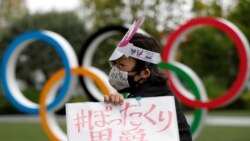 Anti-Olympics protester shows off a placard in front of the Olympic rings monument outside the Japanese Olympic Committee headquarters during their rally, amid the coronavirus disease (COVID-19) outbreak, in Tokyo, Japan May 18, 2021. REUTERS/Issei Kato