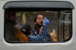 A healthcare worker collects a coronavirus disease (COVID-19) test swab sample from a girl amidst the spread of the disease, at a market area, in the old quarters of Delhi, India, January 7, 2022.