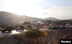 FILE - An armed motorcade belonging to members of Derna's Islamic Youth Council, consisting of former members of militias from the town of Derna, drive along a road in Derna, eastern Libya Oct. 3, 2014.