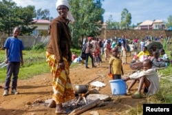 A refugee from the Democratic Republic of the Congo is seen with her children as they prepare a meal near the U.N. High Commissioner for Refugees offices in Karongi district, Rwanda, Feb. 21, 2018.