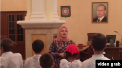 "One should wait for a while to make comments on history,” says Luiza Khatueva, a tour guide at the Akhmad Kadyrov Museum, seen here before a group of school children, with a portrait of President Vladimir Putin in the background.
