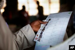 FILE - Kenyan voter holds a presidential ballot at a polling station in the Kibera slum in a general election in Nairobi, Kenya.