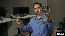 NASA astrophysicist Zaven Arzouman holds a model of the NICER telescope lenses.