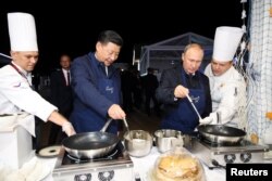Presiden Rusia Vladimir Putin dan Presiden China Xi Jinping membuat pancake saat mengunjungi pameran Far East Street di sela-sela Forum Ekonomi Timur di Vladivostok, Rusia 11 September 2018. (Foto: via Reuters)