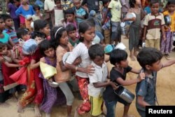 FILE - Rohingya refugee children push each other while waiting outside of an aid distribution center to receive aid supplies in the Palong Khali refugee camp in Cox's Bazar, Bangladesh, Nov. 15, 2017.