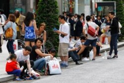 រូបឯកសារ៖ ទេសចរចិនកំពុងឈរនិងអង្គុយនៅលើដងវិថីមួយក្នុងតំបន់ពាណិជ្ជកម្ម Ginza នៅទីក្រុងតូក្យូ ប្រទេសជប៉ុន កាលពីថ្ងៃទី៦ ខែឧសភា ឆ្នាំ២០១៥។