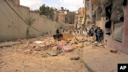 FILE - People walk amid the wreckage of damaged buildings in a street hit by shelling in Aleppo, Syria, Apr. 11, 2015.