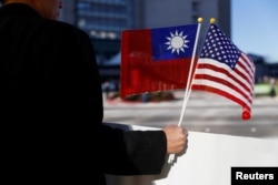 FILE - A demonstrator holds flags of Taiwan and the United States in support of Taiwanese President Tsai Ing-wen during a stopover after her visit to Latin America in Burlingame, Calif., Jan. 14, 2017.