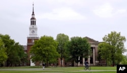FILE- In this May 22, 2018 file photo, students cross The Green in front of the Baker-Berry Library at Dartmouth College in Hanover, N.H. (AP Photo/Charles Krupa, File)