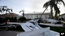 A roof is strewn across a home's lawn as Rick Freedman checks his neighbor's damage from Hurricane Irma in Marco Island, Fla., Sept. 11, 2017.