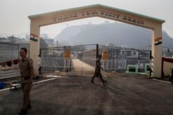 An Indian army soldier, center, and a Mizo policeman patrol at the India-Myanmar border gate , in Chaamphai village, in Mizoram, India, Saturday, March 20, 2021.