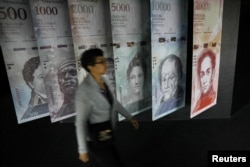 Seorang peremouan berjalan di dekat spanduk uang Venezuela, bolivar, yang dipamerkan di Gedung Bank Sentral Venezuela di Caracas, Venezuela 23 Mei 2017. (Foto: REUTERS/Carlos Barria)