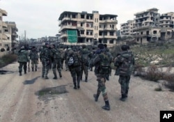 FILE - Syrian government troops and allied militiamen walk inside the key town of Salma in Latakia province, Syria, Jan 12, 2016.