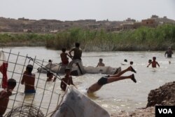 As temperatures soar well past 40 C (104 F) almost every day, children in this camp rip open a fence to swim in a nearby stream in Hassan Sham, Iraqi Kurdistan, May 29, 2018. (H. Murdock/VOA)