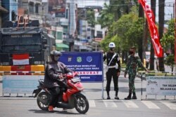 Sejumlah tentara menjaga penyekatan PPKM untuk meredam penyebaran pandemi COVID-19 di Medan, Sumatera Utara, Kamis, 15 Juli 2021. (Foto: Binsar Bakkara/AP)