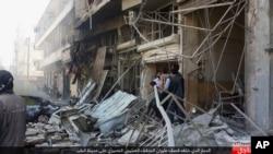 In this Oct. 5, 2015 photo released by the Rased News Network, a Facebook account affiliated with Islamic State militants, which has been authenticated based on its contents and other AP reporting, people gather at the site of an airstrike in Al-Bab on the outskirts of Aleppo, Syria.