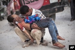 FILE - A Syrian man cries as he holds the lifeless body of his son, killed by the Syrian Army, near Dar El Shifa hospital in Aleppo, Syria, Oct. 3, 2013.