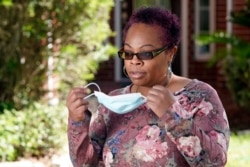 Parent and teacher Stacey Pugh takes off her mask to be photographed outside her home Monday, July 13, 2020, in Humble, Texas. While children have proven to be less susceptible to the coronavirus, teachers are vulnerable.