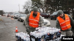 Michigan National Guard members distribute water to a line of residents in their cars in Flint, Michigan, Jan. 21, 2016.